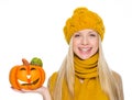 Happy girl in hat and scarf holding jack-o-lantern