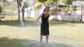 Happy girl is having fun in puddle under the water jet in park.