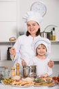 Happy girl and her mother are standing with ladle and soup together Royalty Free Stock Photo
