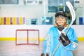 Happy girl in hockey uniform posing with stick