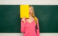 Happy girl holding announcement while stand in classroom. Student with backpack. High school education. Great