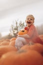 Happy girl holding a big pumpkin in her hands.