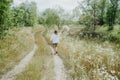 Happy girl holding bouquet of field flowers having a walk in the countryside. Rear view Royalty Free Stock Photo