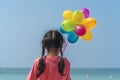 Happy girl holding colorful air balloons on the beach summer times. Happiness playful child joy holiday while travel to summer Royalty Free Stock Photo