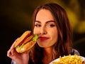 Happy girl holding fastfood hamburger and fried potatoes .