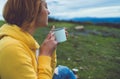 Happy girl holding in hands cup of hot tea on green grass in outdoors nature park top view, beautiful woman hipster enjoy drinking Royalty Free Stock Photo