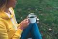 Happy girl holding in hands cup of hot tea on green grass in outdoors nature park top view, beautiful woman hipster enjoy drinking Royalty Free Stock Photo