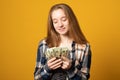 Happy girl holding money banknotes and celebrating on yellow background Royalty Free Stock Photo