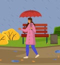 Happy girl holding red umbrella in raining walking in cool weather in city park enjoys the rain