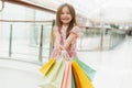Happy girl holding shopping bags at the mall. A little girl holds multi-colored pastel bags in her hands close to the camera. The