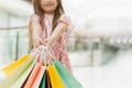 Happy girl holding shopping bags at the mall. A little girl holds multi-colored pastel bags in her hands close to the camera. The