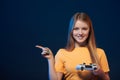 Happy girl holding video game joystick pointing finger to side