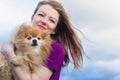 Happy girl hugging her dog. young woman hold her red, ginger pomeranian spitz. female owner and faithful pet outdoors.