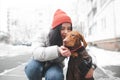 Happy girl hugs and kisses a beautiful orange dog on the background of a winter street and buildings. Love to the dog. Magyar