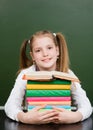 Happy girl hugs pile books near empty green chalkboard Royalty Free Stock Photo