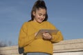 Happy girl with a ipad in a park on a bridge with a yellow sweater