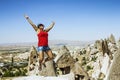 Happy girl jumping on the background of the cave city in Cappadocia, Turkey