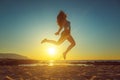 Happy girl jumping on the beach against beautiful sunset Royalty Free Stock Photo