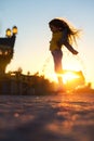 Happy girl jumping on the beach sand and enjoying the sunset in the fun city Royalty Free Stock Photo