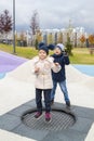 happy girl is jumping on trampoline and disgruntled boy is angry and can not wait for his turn to jump on modern playground Royalty Free Stock Photo