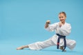 Happy girl in kimono standing in karate stance in studio