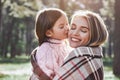 Happy, girl kisses her beautiful mother in forest are covered with blanket