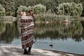 Happy, girl kisses her beautiful mother near lake are covered with blanket