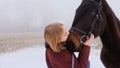 A happy girl kisses her beloved horse in a field during fog Royalty Free Stock Photo