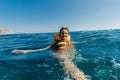 happy girl in a life jacket swims in the water in the sea