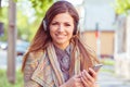 Happy girl listening music with headphones on a smartphone in the street on a autumn sunny day Royalty Free Stock Photo