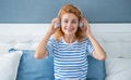 Happy girl listening to music on bed, leisure. Woman enjoying leisure pastime at home Royalty Free Stock Photo