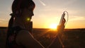 Happy girl listening to music on a smartphone in the rays of a beautiful sunset. Young girl in headphones and with the