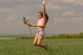 Happy girl with long hair holding a colored windmill and jumps Royalty Free Stock Photo