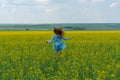 A happy girl with long hair runs across a yellow flower field. Hair develop