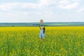 A happy girl with long hair is standing on the grass on a green field with a bright windmill in her hands. Concept of summer, Royalty Free Stock Photo