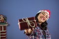 Happy girl looking into the camera, smiling and showing off her little Christmas gift box. she is wearing a lumberjack shirt and a