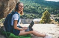 Happy girl looks at camera enjoys freedom in mountains listening to music on headphones and digital tablet, traveler woman Royalty Free Stock Photo