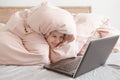 Happy girl lying in bed under blanket and learning in virtual online school class. Kid working on a laptop Internet at home. Child Royalty Free Stock Photo