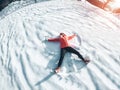 Happy girl making the angel shape on fresh snow - Young woman having fun on high mountains during winter vacation - Holiday and Royalty Free Stock Photo