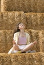 Happy girl meditating or relaxing in nature. Young woman on sitting lotus yoga pose on hay background Royalty Free Stock Photo