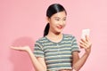 Happy girl with mobile phone holding presenting something imaginary, open hand palm for copy space for product studio shot pink