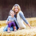 Happy girl and mother having fun with hay on a farm Royalty Free Stock Photo