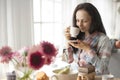 Happy girl with a mug of fragrant coffee in hands. Good breakfast at home in the living room by the window. Free space for text. Royalty Free Stock Photo