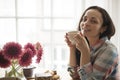 Happy girl with a mug of fragrant coffee in hands. Good breakfast at home in the living room by the window. Free space for text. Royalty Free Stock Photo