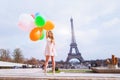 Happy girl with multicolored balloons near Eiffel tower in Paris