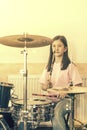 Happy girl in music therapy by playing drum kit on music room. Beautiful young girl drummer with drumsticks playing drums and