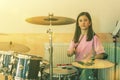 Happy girl in music therapy by playing drum kit on music room. Beautiful young girl drummer with drumsticks playing drums and Royalty Free Stock Photo