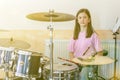 Happy girl in music therapy by playing drum kit on music room. Beautiful young girl drummer with drumsticks playing Royalty Free Stock Photo