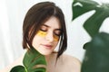 Happy girl with natural skin and lifting anti-wrinkle collagen patches under eyes and green palm leaf. Portrait of beautiful young Royalty Free Stock Photo