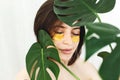 Happy girl with natural skin and lifting anti-wrinkle collagen patches under eyes and green palm leaf. Portrait of beautiful young Royalty Free Stock Photo